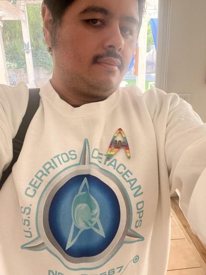 Me wearing a U.S.S. Cerritos Cetacean Ops sweatshirt with a 60th anniversary Pride badge.